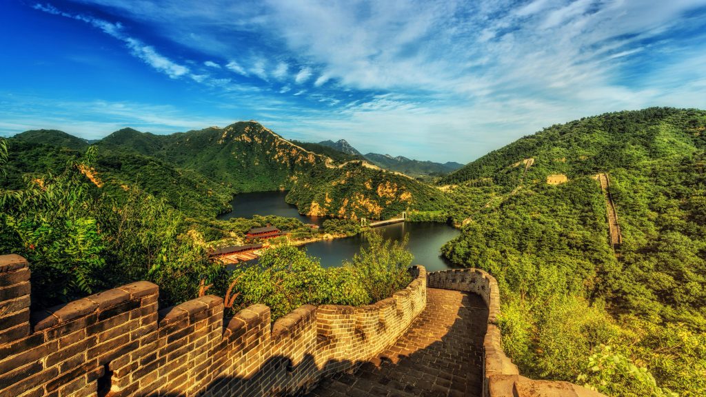 Breathtaking landscape of the Great Wall of China surrounded by lush green hills and vibrant skies.