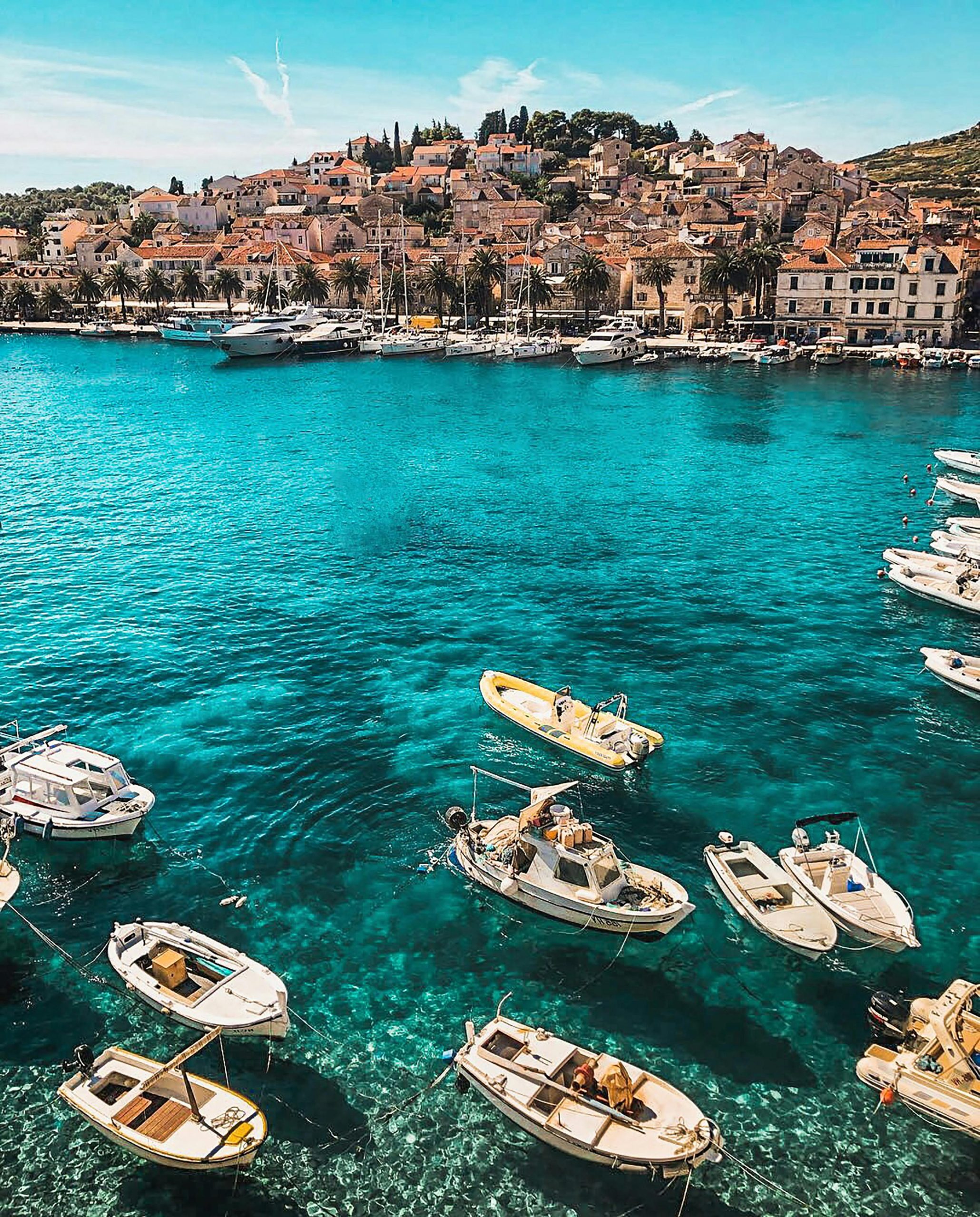 Boats in the vibrant blue waters of Hvar, Croatia, showcasing a charming coastal town under sunny skies.