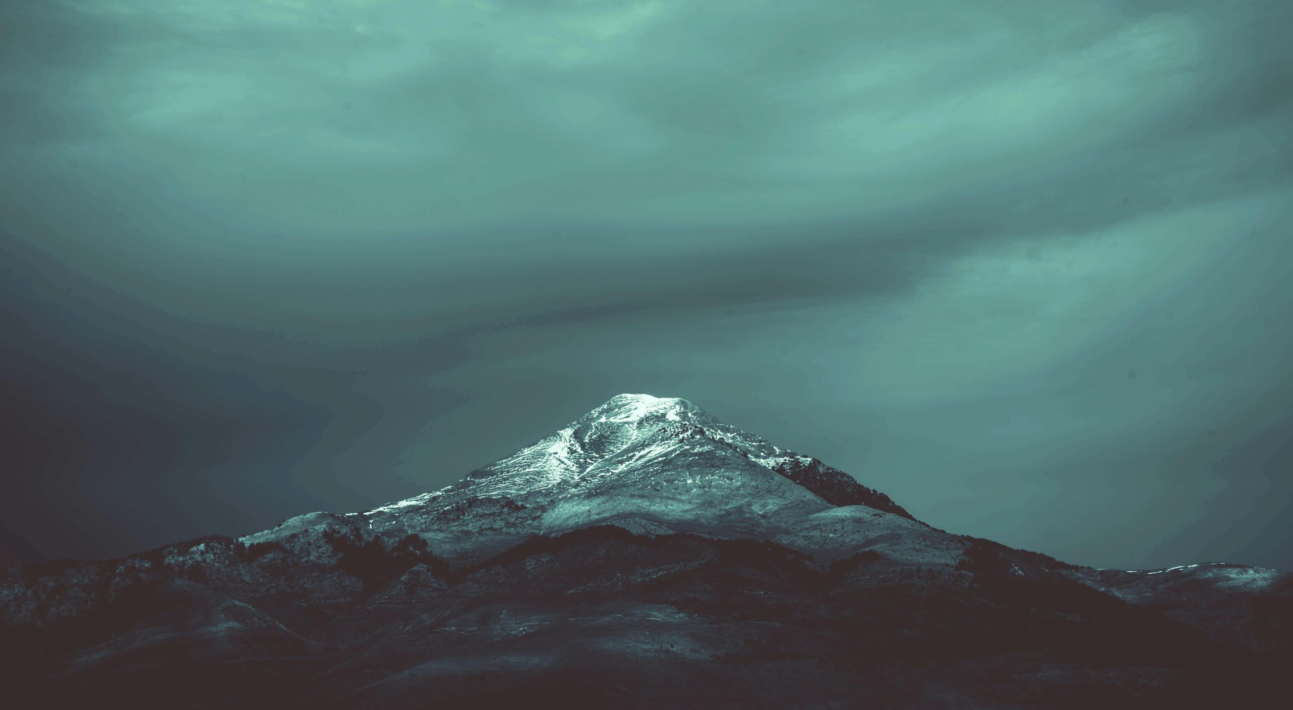 A dramatic snow-capped mountain peak in Algeria set against a moody sky, perfect for winter landscapes.